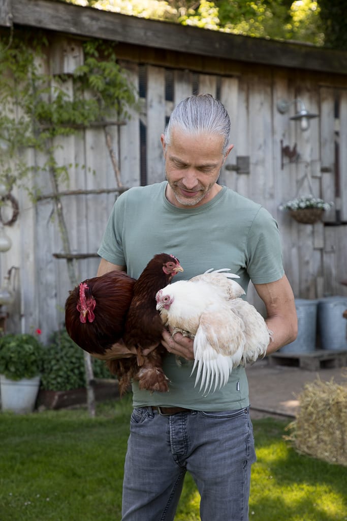 Ein Mann hält zwei Hühner in der Hand