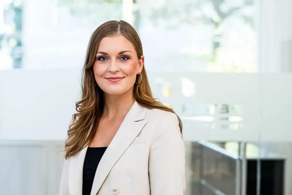 Portrait einer Frau in einem lichtdurchfluteten Büro.