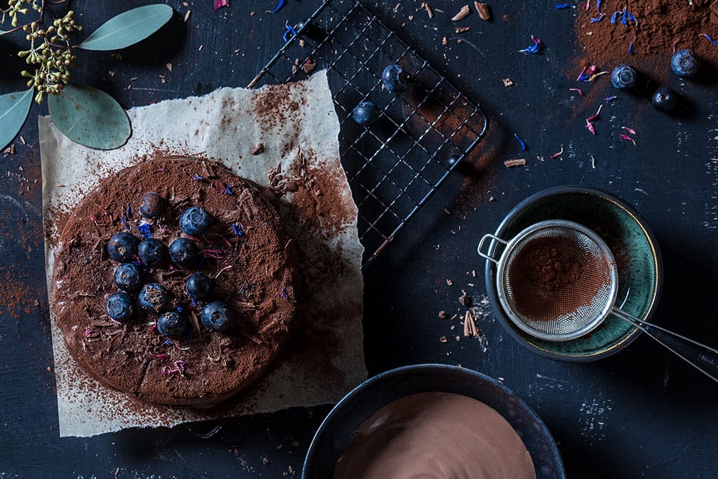 Foodfotografie und Foodstyling aus Köln. Frischer Obstsalat mit Orangenstücken, Äpfeln und Beeren auf einem weißen Teller
