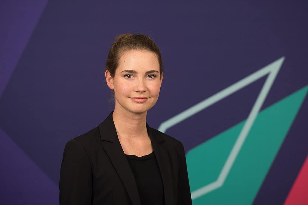 Mitarbeiterporträts für das Unternehmen Yougov in Köln. Frau vor einem blauen Hintergrund.