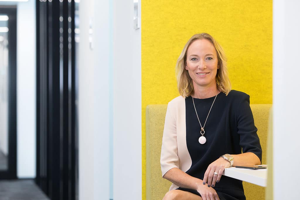 Mitarbeiterfotos - Frau in einem gelben Raum. Sie lächelt in die Kamera.