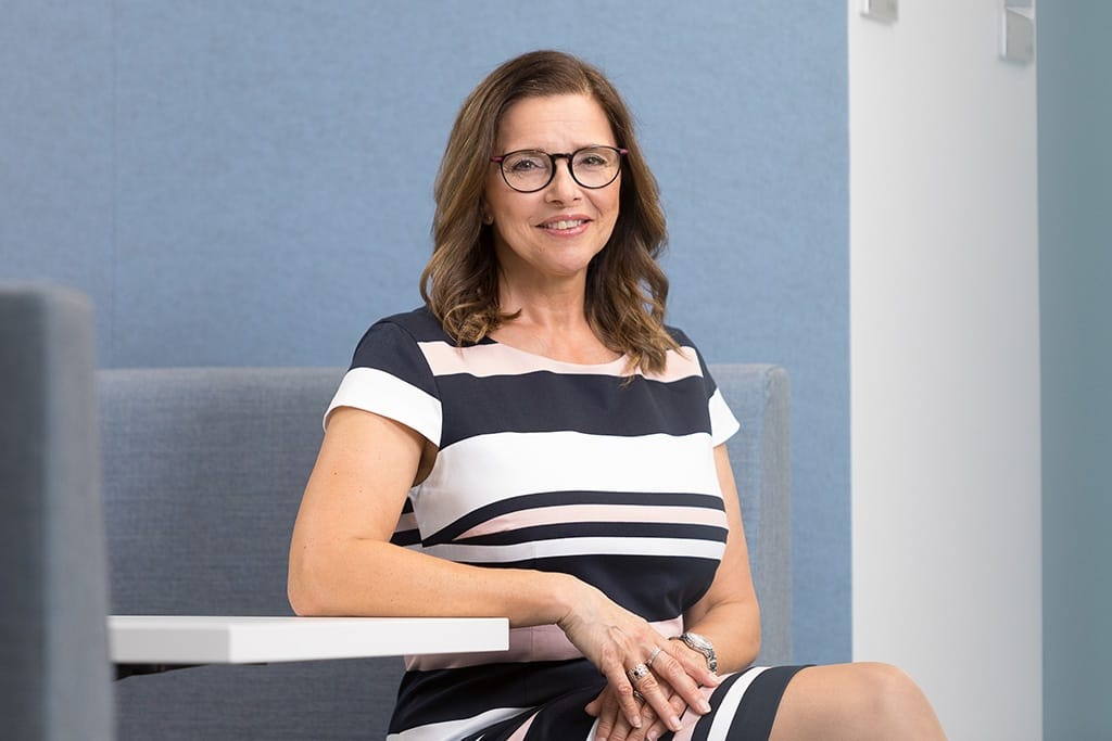 Frau in gestreiftem Kleid sitzt. 