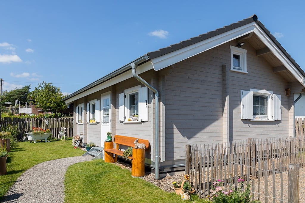 Graues Ferienhaus mit einem schönen Garten im Vordergrund.