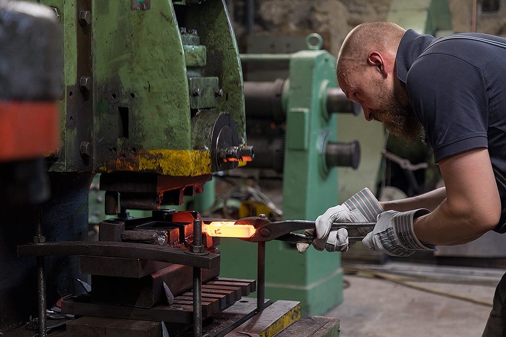 Brennendes Eisen wird im Ofen bearbeitet. Das Licht ist eher dunkel.