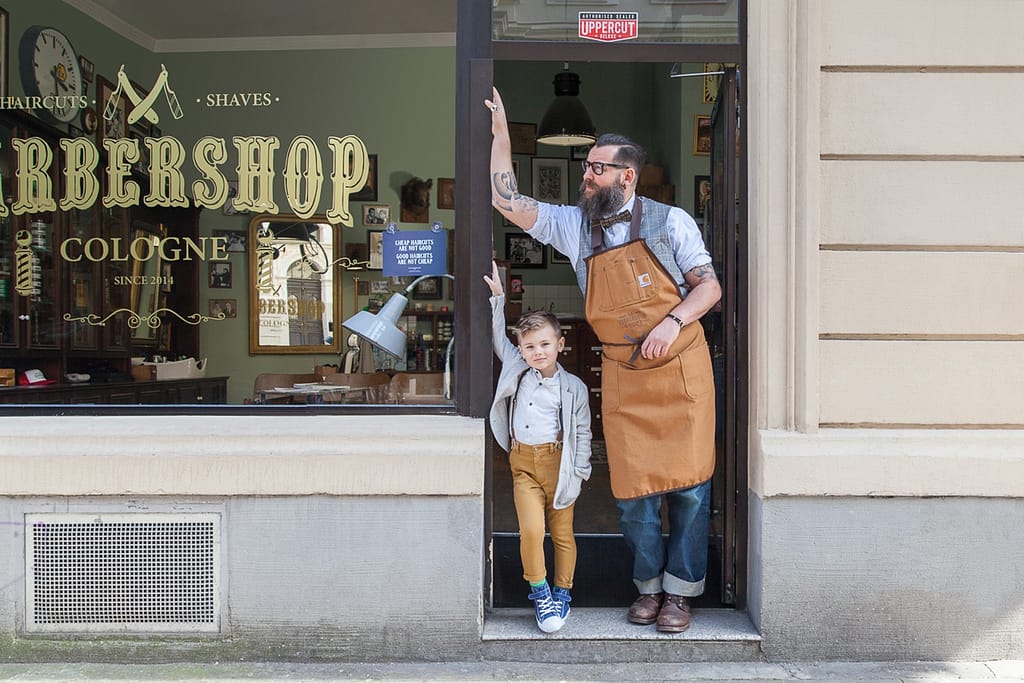 Ein Mann und ein kleiner Junge stehen vor dem Barber Shop Cologne.