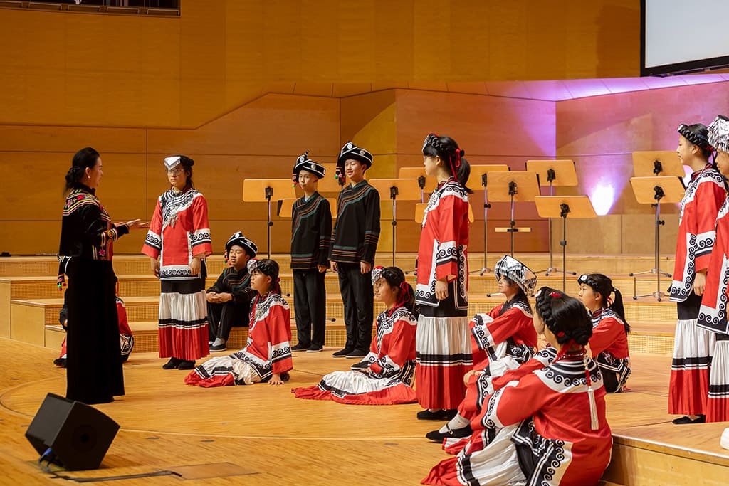 Künstlerfotografie. Ein beeindruckender Moment der Aufführung des chinesischen Chors in der Philharmonie Essen. Der Chorleiter dirigiert die Sänger, die in traditioneller Kleidung auf der Bühne stehen.