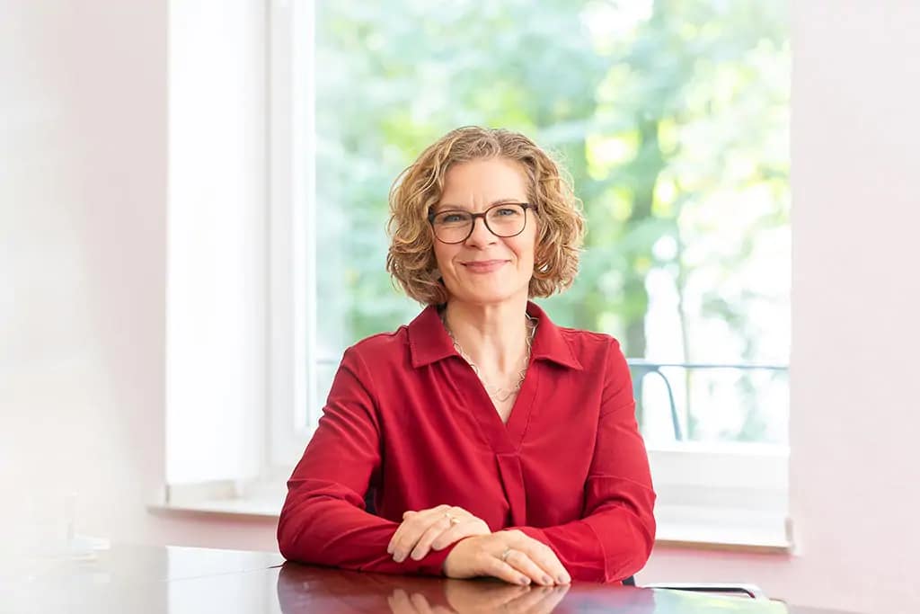 Frau sitzt am Schreibtisch - klassisch porträtiert.