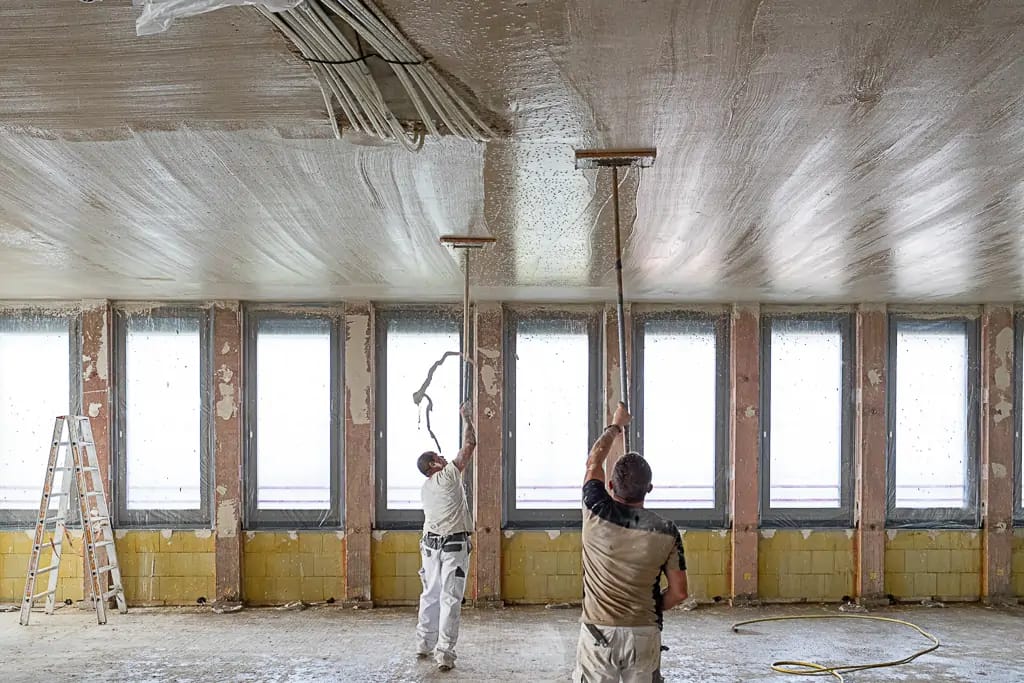 Zwei Männer streichen eine Decke