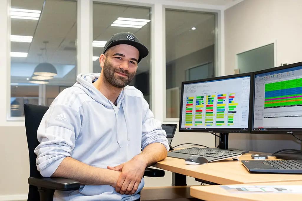 Klassisches Porträt Shooting in einem Kölner Unternehmen. Ein Mann sitzt an einem Schreibtisch und lacht in die Kamera.