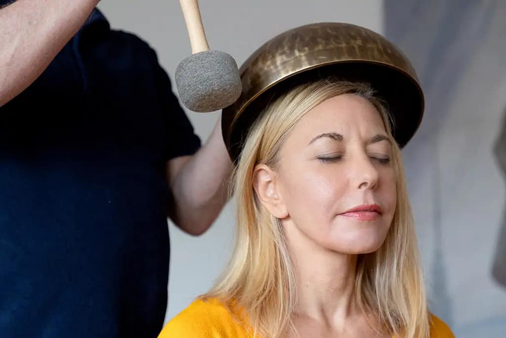 Klangschalen Porträt - Eine Schale wird über den Kopf einer Frau angeschlagen