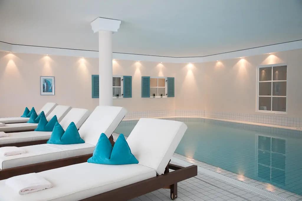 Haubers Resort, Oberstaufen - Eine Schwimmhalle mit Liegen im Vordergrund