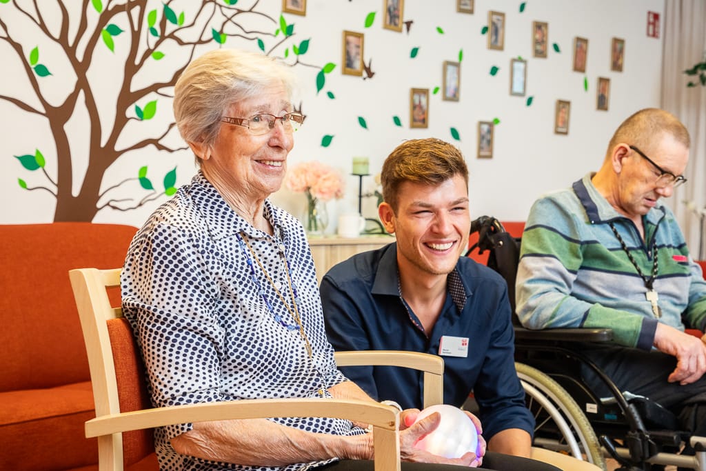 Ein Pfleger hat Freude mit einer Seniorin